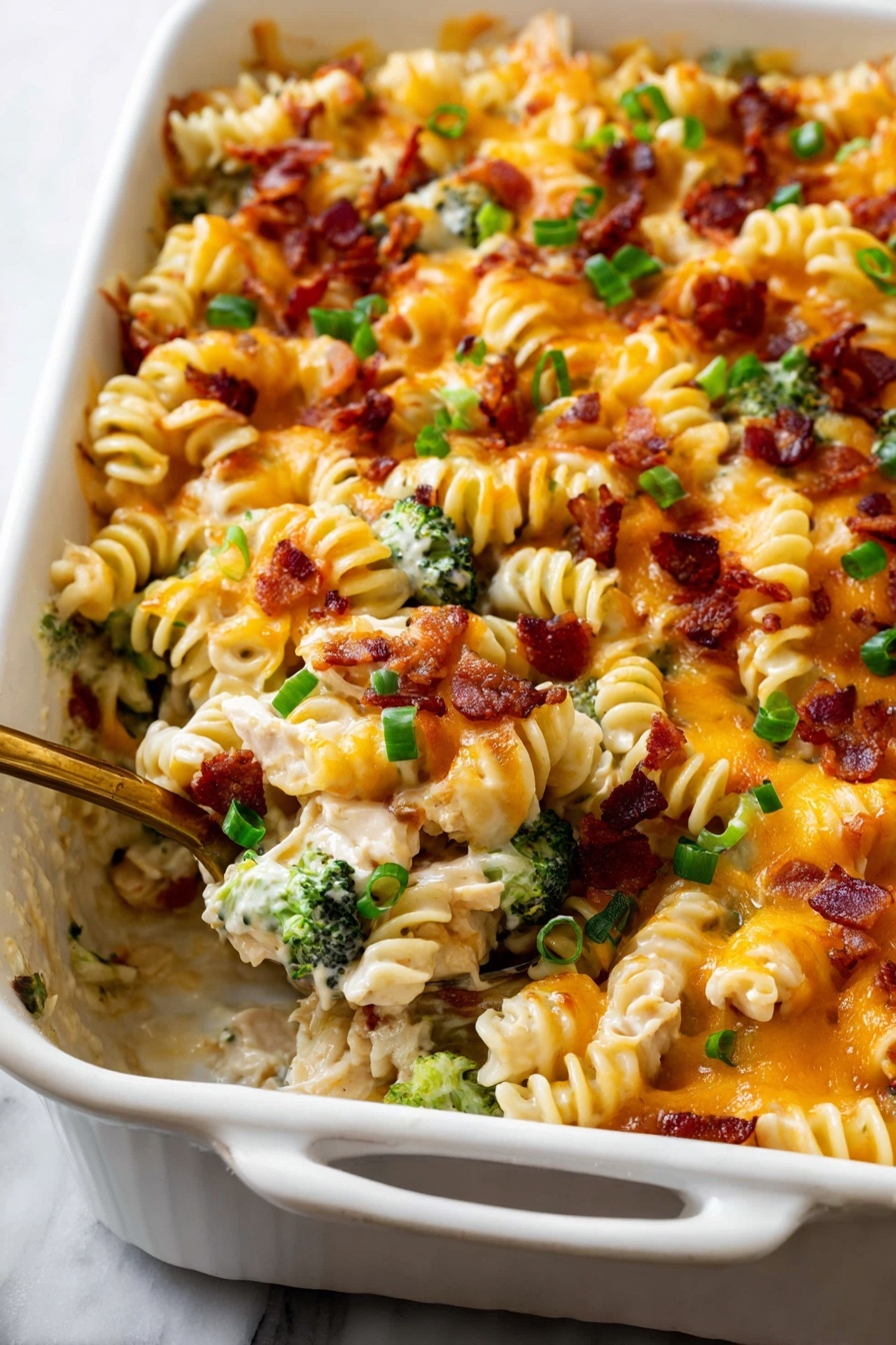 The dish is a white rectangular baking dish filled with a creamy pasta bake made with spiral-shaped pasta. The top layer is melted golden-orange cheese with bits of crispy brown bacon scattered across. Bright green chopped spring onions are sprinkled over the top, adding pops of color. Underneath the cheese, visible pieces of green broccoli peek through the pasta. A golden spoon is scooping out some pasta, showing the creamy mixture with white chicken pieces mixed with pasta and vegetables. The dish sits on a white marbled surface. photo taken with an iphone --ar 2:3 --v 7