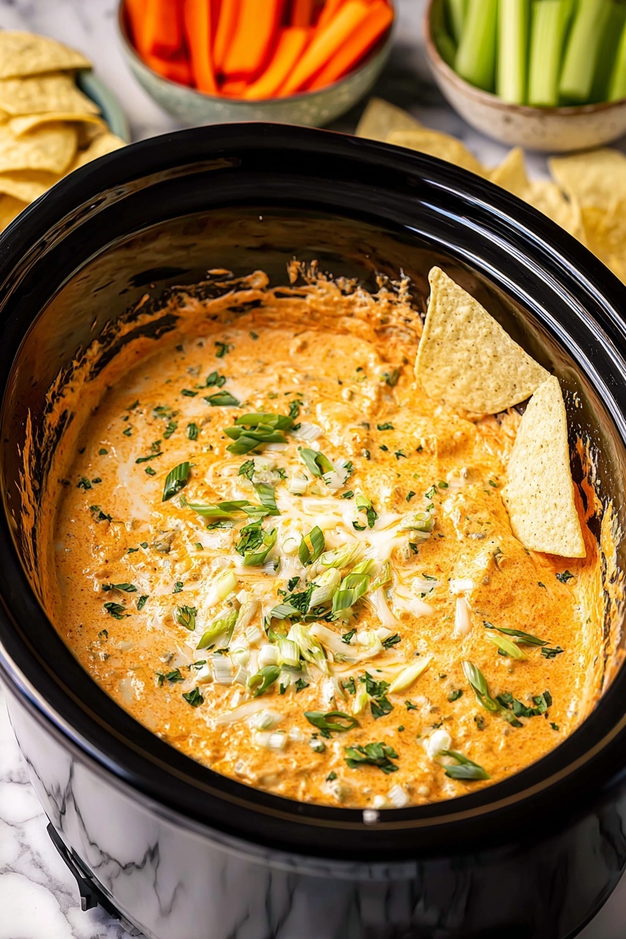 The image shows a black slow cooker filled with a creamy orange dip that has a smooth, mixed texture. On top of the dip, there are small chunks of melted yellow and white cheese scattered around, along with chopped green onions and sprinkles of fresh green herbs. A few light yellow tortilla chips are partly dipped into the mixture, resting on the surface near the edge. The background has white marbled texture with some carrot sticks and light yellow food items visible around the edge of the cooker. Photo taken with an iphone --ar 2:3 --v 7