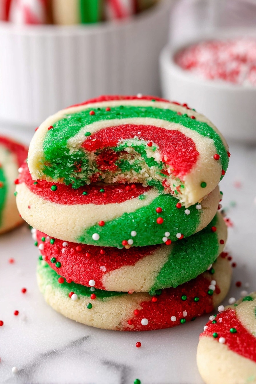 A pile of round cookies with three spiral layers in red, white, and green colors, arranged closely on a white plate. Each cookie's outer edge is decorated with small red, green, and white round sprinkles. The cookies have a smooth, slightly textured surface with clear, even swirls. Underneath the plate is a white marbled surface, and a green and white checkered cloth is softly folded in the background. Photo taken with an iphone --ar 2:3 --v 7