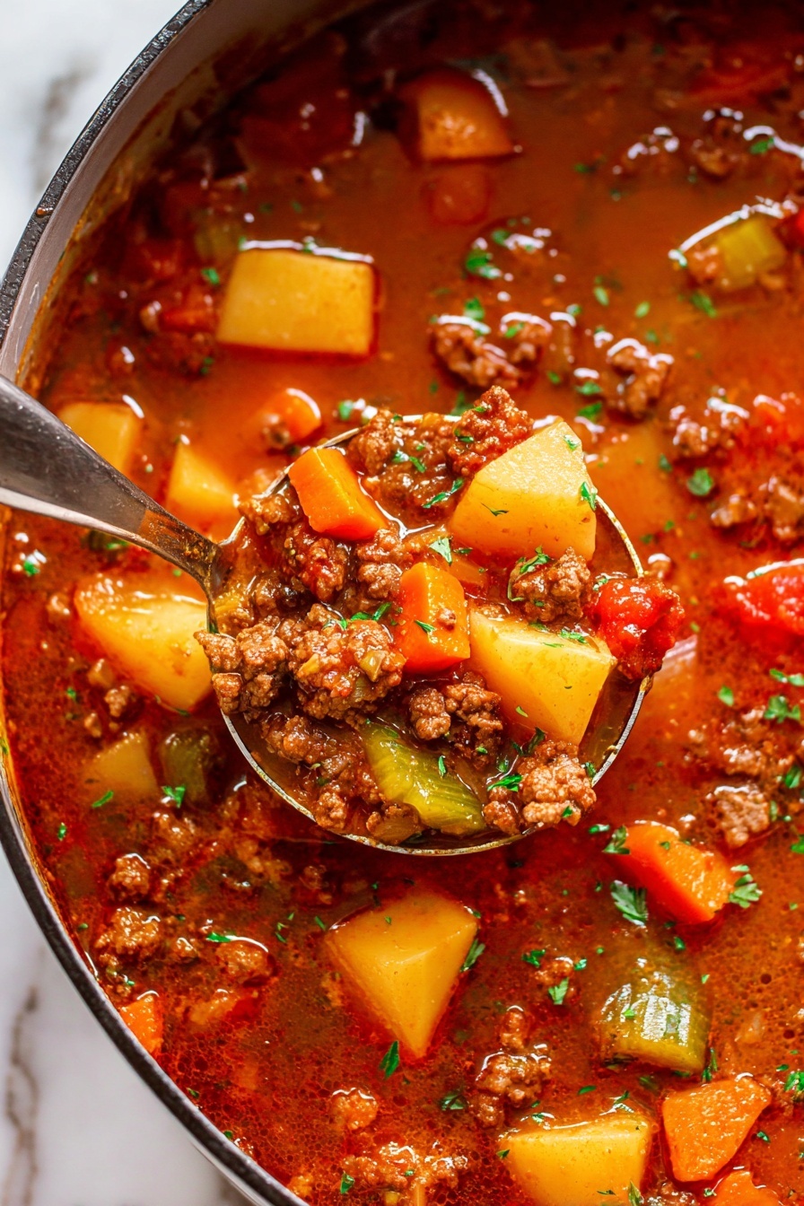 The image shows a close-up of a thick stew with many layers of ingredients in a rich reddish-brown broth. Large chunks of golden yellow potatoes, bright orange carrot pieces, and small green celery bits float among tasty-looking browned ground meat. There are also visible pieces of red tomatoes adding variety to the textured mix. A silver ladle scoops some of the stew, showing a focused mix of the vibrant vegetables and meat with small green herbs sprinkled over it. The stew sits in a pot on a white marbled texture surface. photo taken with an iphone --ar 2:3 --v 7