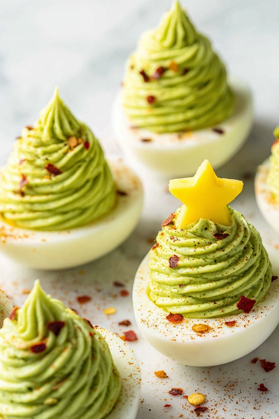 The image shows five deviled eggs placed on a white marbled surface, each with two clear layers. The bottom layer is the white smooth egg half, topped with a tall, swirled, light green creamy filling in a spiral pattern, giving a soft texture. Red pepper flakes are scattered on the green filling and the white edge of the egg, adding small red and orange spots around the dish. One egg stands out with a yellow star-shaped piece placed on top of the green filling, acting like a decoration. The overall look is neat and fresh with a mix of smooth and textured layers. Photo taken with an iphone --ar 2:3 --v 7