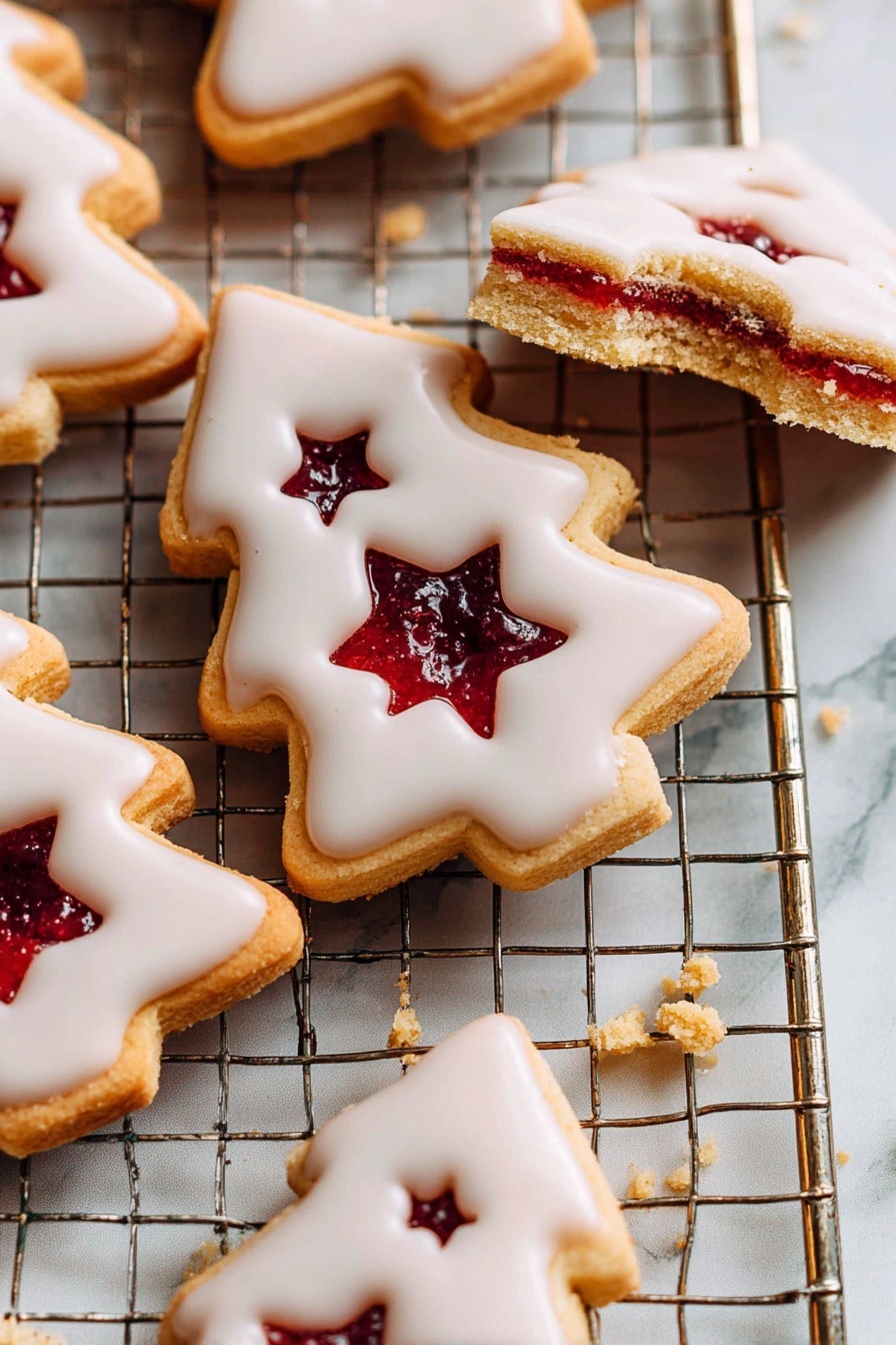 The image shows several Christmas tree-shaped cookies on a metal cooling rack placed over a white marbled surface. Each cookie has two layers: a bottom golden brown layer and a top layer covered with smooth white icing. The top layer has a small star-shaped hole in the center, revealing a deep red jam filling. One cookie at the top of the image has a bite taken out of it, showing the inner texture and the jam more clearly. Crumbs are scattered around this cookie, adding to the cozy feel. The photo is bright with soft natural light highlighting the shiny icing and jam. photo taken with an iphone --ar 2:3 --v 7