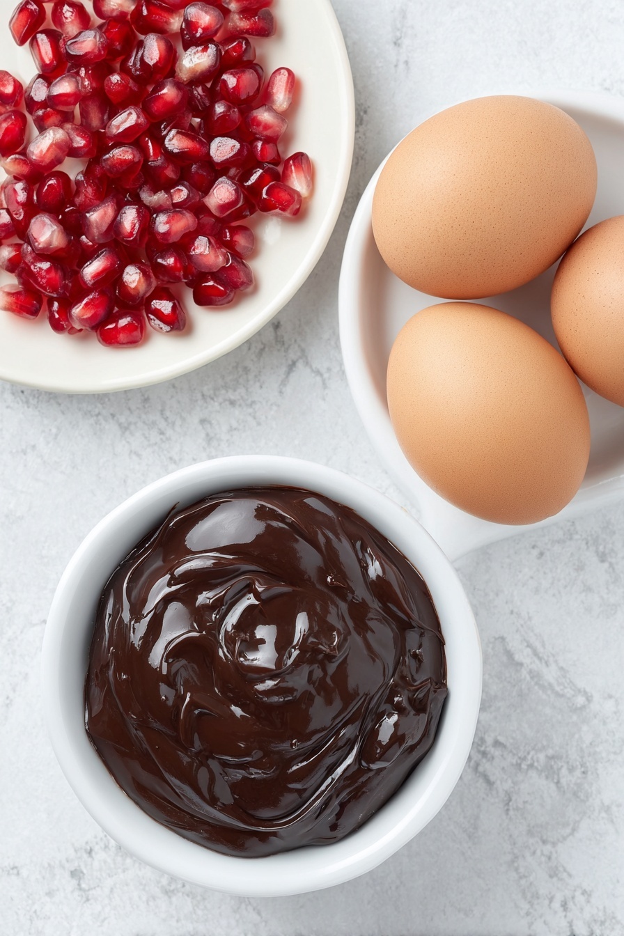Flat lay of a small white ceramic bowl filled with glossy melted dark chocolate, a handful of bright red pomegranate seeds scattered neatly beside it, and a smooth white ceramic plate holding two whole uncracked brown eggs, all arranged in perfect symmetry and balanced proportions, placed on a clean white marble surface, soft natural light, photo taken with an iPhone, professional food photography style, fresh ingredients, white ceramic bowls, no bottles, no duplicates, no utensils, no packaging --ar 2:3 --v 7 --p m7354615311229779997