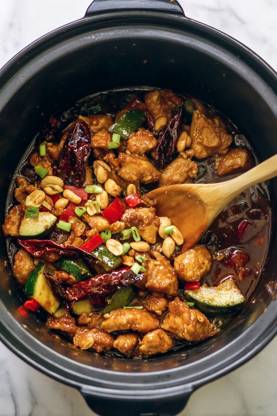The image shows a pot with several layers of food. The bottom layer is a dark brown sauce covering the base. On top of this are many golden-brown pieces of chicken spread evenly around the pot. Mixed with the chicken are slices of dark red dried chili peppers and bright green zucchini pieces, some sliced in half. There are also small red pieces of bell pepper adding color. Light brown peanuts are spread across the dish, creating texture and contrast. A wooden spoon rests in the middle, partially covered with sauce and food, suggesting the dish is being stirred. Small green onion slices are scattered over the top for garnish. The pot is black inside, and the scene is set on a white marbled surface. photo taken with an iphone --ar 2:3 --v 7
