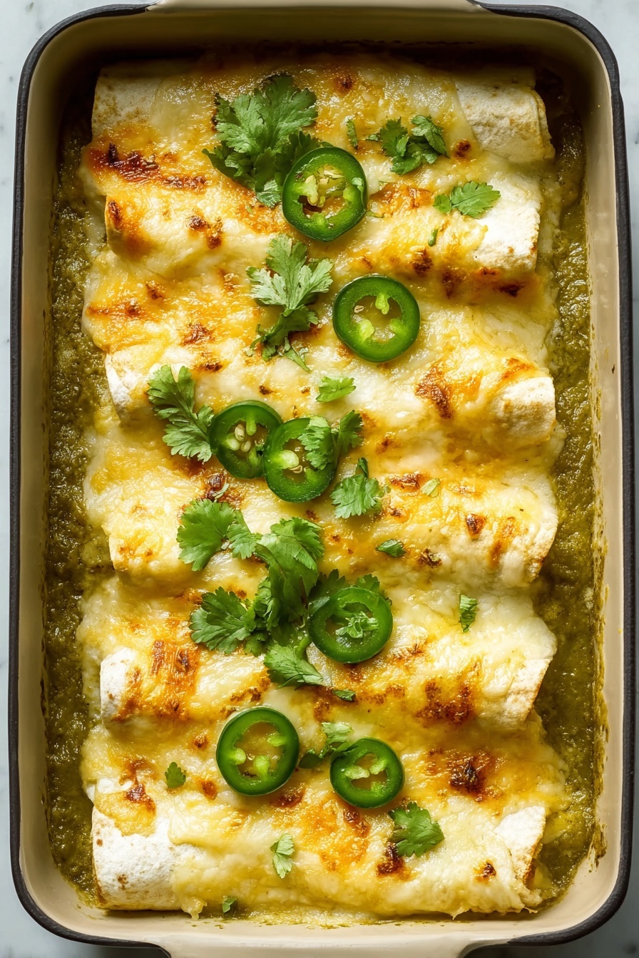 A baking dish with four rolled tortillas laid side by side, covered in a layer of melted golden cheese with some browned spots, sitting on top of a thick green sauce that fills the dish's base; bright green slices of jalapeño and fresh cilantro leaves are scattered over the top, adding pops of color and texture against the creamy cheese and soft tortillas, all resting on a white marbled surface photo taken with an iphone --ar 2:3 --v 7