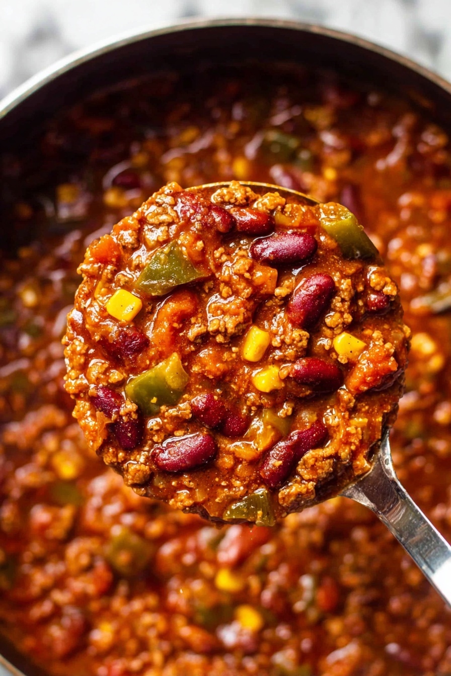 The image shows a close-up of a thick stew with three main visible layers blended together: a base of rich reddish-brown sauce soaked with spices, mixed with chunks of cooked ground meat, dark red kidney beans, small cubes of bright yellow corn, and diced green bell peppers. The stew looks hearty and textured, with chunks and bits evenly spread throughout, some areas shiny with moisture. A shiny metal ladle holds a scoop of the stew in the center of the frame, emphasizing the thickness and chunky ingredients. The background is the same stew filling the pot around the ladle, set on a white marbled surface. Photo taken with an iphone --ar 2:3 --v 7