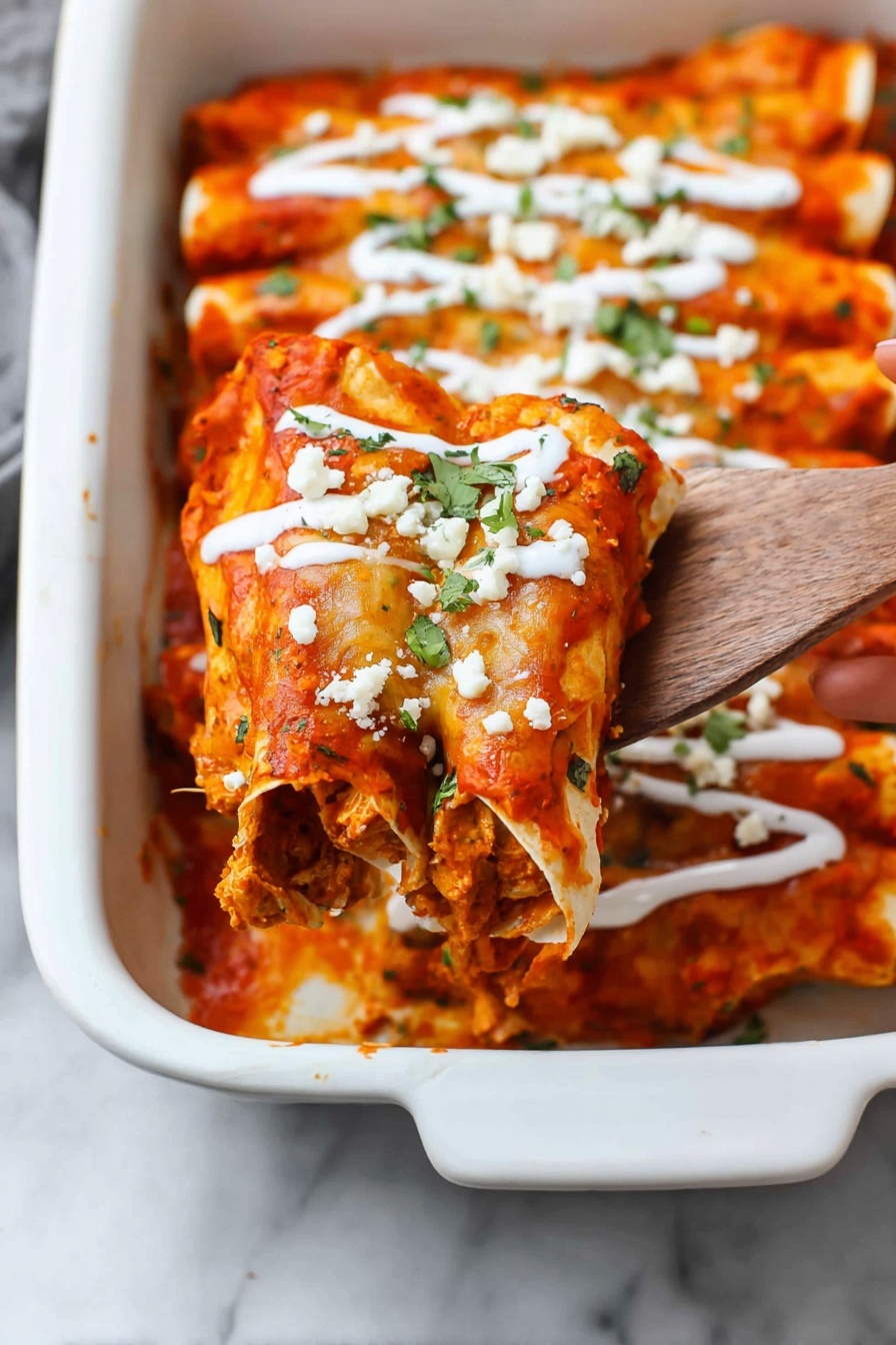 A close-up of a white baking dish holding rolled enchiladas layered with bright red sauce and melted golden cheese on top, with visible orange and brown spots from baking. The enchiladas are piped with thin white creamy sauce lines and sprinkled with small pieces of white cheese and green herbs. A wooden spatula with a woman's hand is lifting one enchilada, showing the dense, textured filling inside with layers of sauce and cheese. The dish sits on a white marbled surface. Photo taken with an iphone --ar 2:3 --v 7